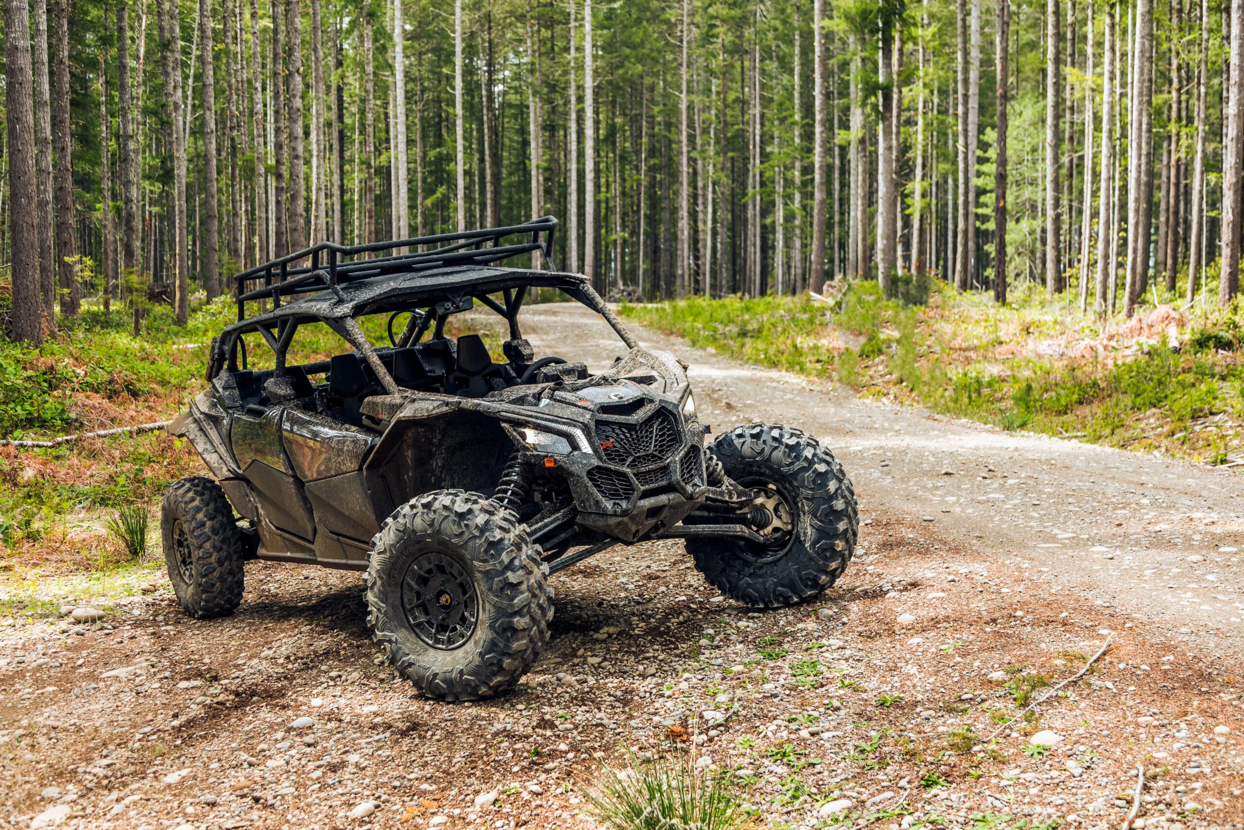 Muddy off-road vehicle on a gravel forest trail.