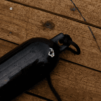 Mad Dog Inflatable Boat Fender Black inflatable boat fender with rope on wooden dock.