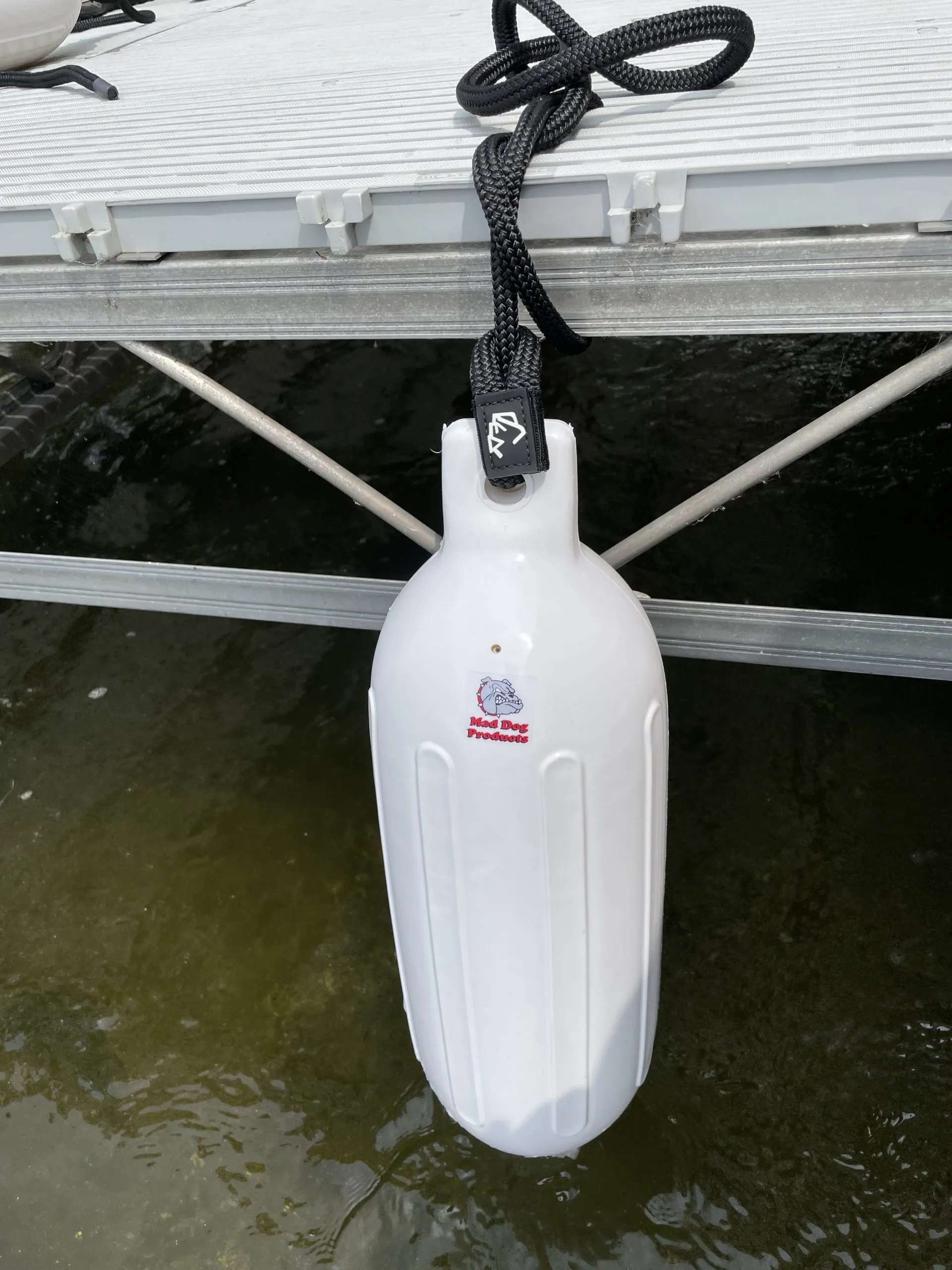 Mad Dog Inflatable Boat Fender White inflatable boat fender attached to dock with rope.